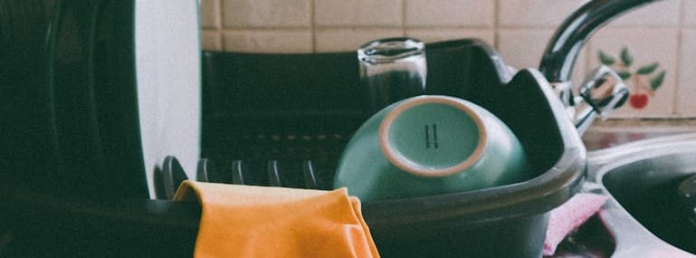 Cozy kitchen setup featuring a dish rack, dishes, and yellow gloves, ideal for a homey atmosphere.